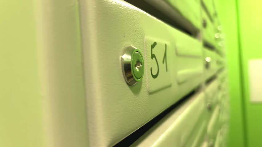 Man opening an apartment mailbox marked number fifty, residential mail delivery and everyday building access, urban communication concept.