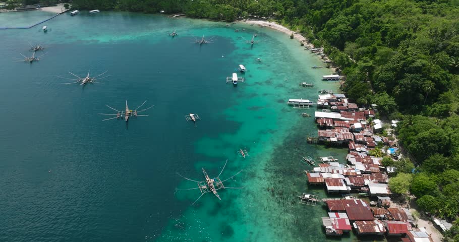 Traditional fishing boats floating over the blue sea, stilt house in coastline of Samal Island, Davao. Philippines.