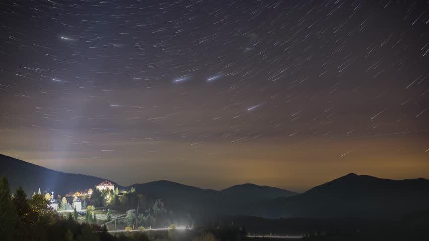 Starry sky with white clouds floating above town in highland