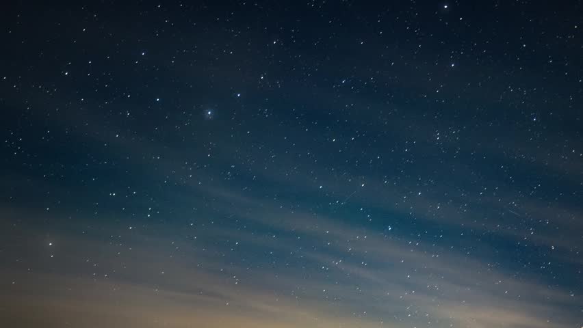 Night starry sky with light pink clouds floating at twilight