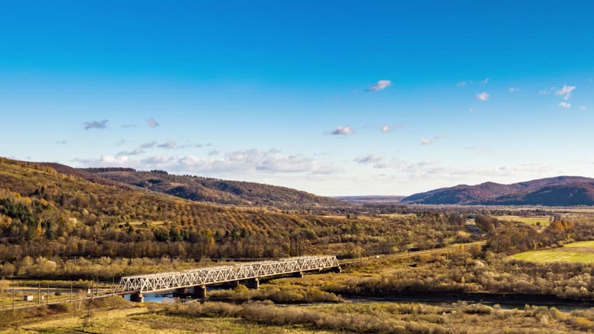 Railroad bridge over river in highland with colorful trees