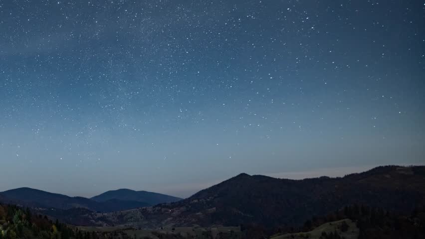 Starry sky with white clouds floating above town in highland