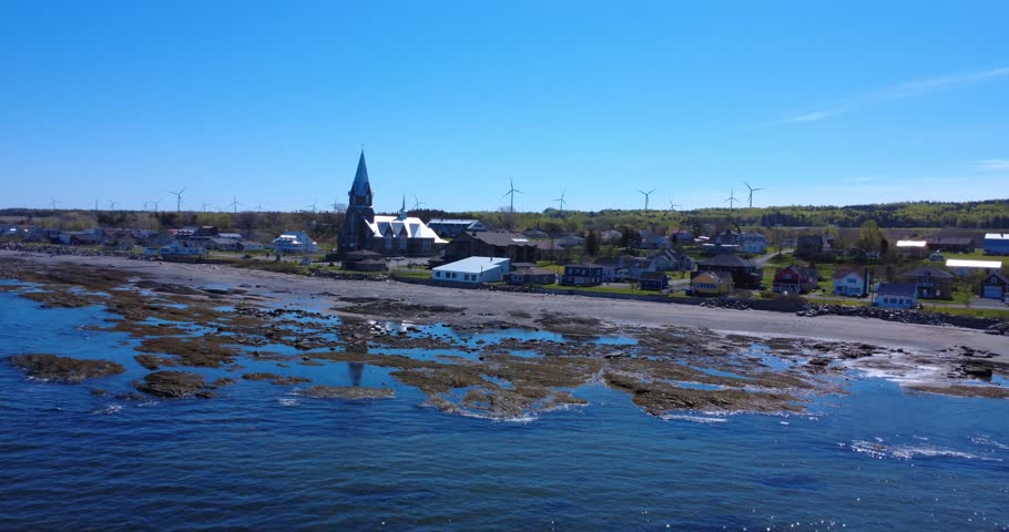 Coastal landscape featuring exposed tidal pools, colorful houses and historic architecture in Bas-Saint-Laurent.