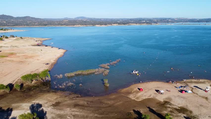 Title:
Granite Bay, Folsom Lake, California - July 31, 2026: Aerial lateral shot along shoreline with swimmers and low water levels