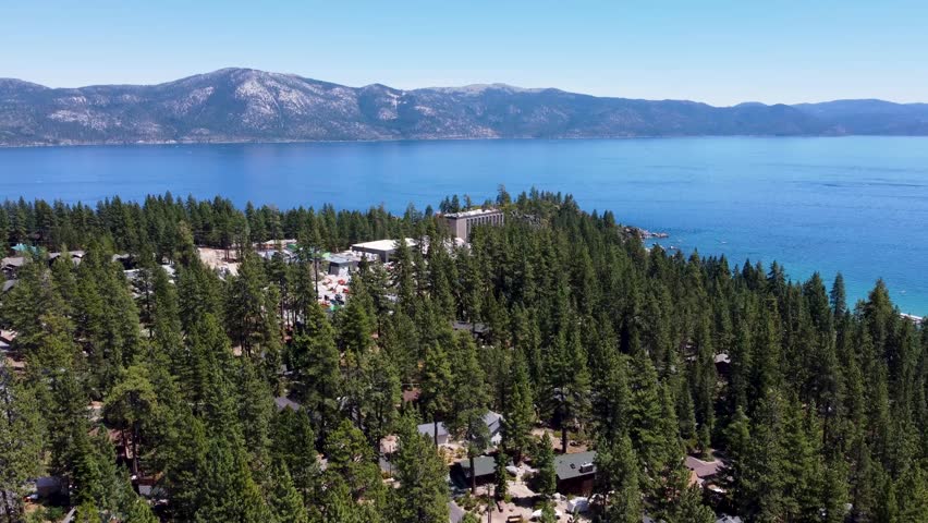 North Lake Tahoe: Lateral aerial shot of forested shoreline and mountains near Crystal Bay, NV