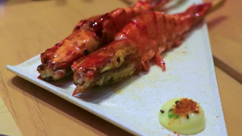 Luxury Marriott Phuket sushi restaurant serving two large grilled shrimp skewers on plate placed on wooden table in Thailand.