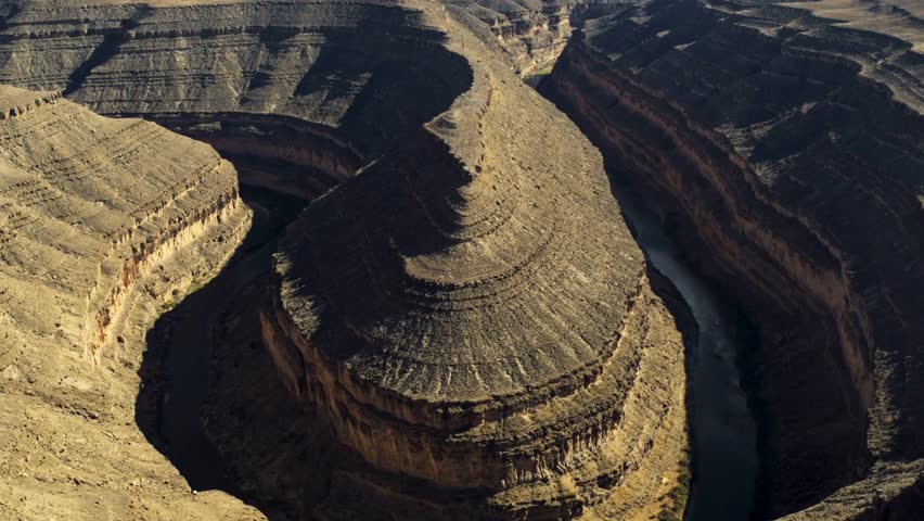 Aerial view of a winding river horseshoe bend flowing through a deep rocky canyon with steep layered rock formations