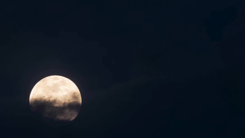 Bright full moon partially covered by soft dark clouds drifting across dark night sky during calm peaceful clear night TIME LAPSE VIDEO