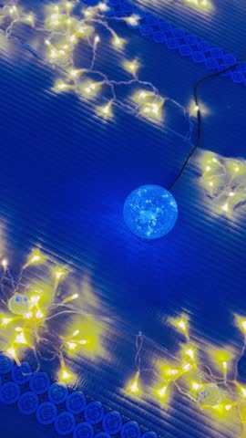 A serene and captivating high-angle view of warm fairy lights and a glowing spherical lamp beautifully decorated on traditional blue tatami mats in Shiga, Japan.