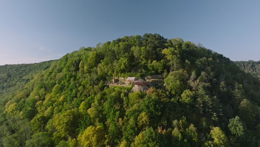 France, Bourgogne-Franche-Comté, Jura (39), Conliège: High-angle scenic view of the historic Hermitage of Conliège surrounded by dense forest in a valley. Located in the Jura department, this historic religious landmark showcases traditional architecture and pristine French nature.