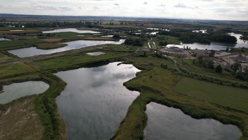 Aerial footage showing a vast landscape with lakes, a quarry, and lush green fields