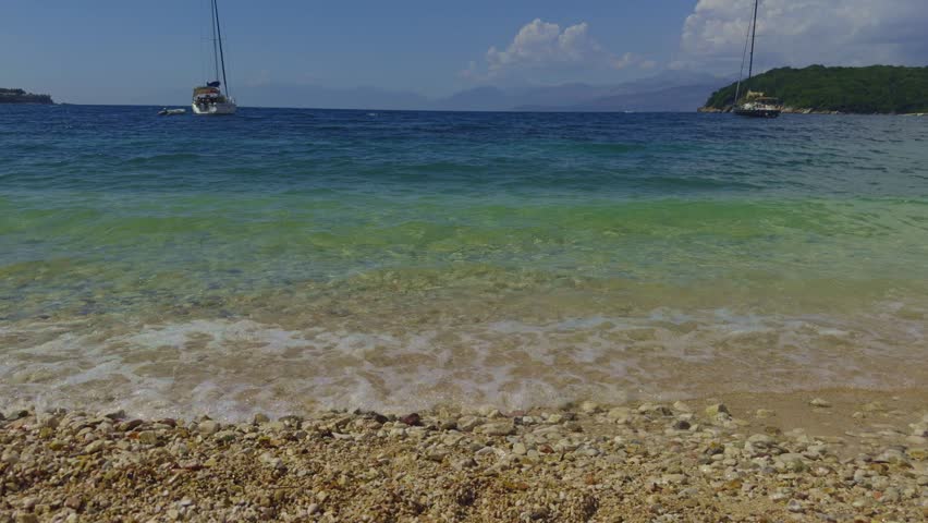 Wave Splashing Over Pebbles At Sea. Close Up Sea Ocean Beach In Slow Motion. Waves Crashing In Background And Wave Splashing Over Pebbles. Air Bubble On Pebbles. Vocation Or Summer Holiday Concept