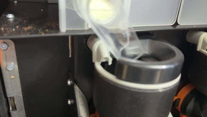 water flowing into mixer cup during coffee vending machine rinse cycle, automatic cleaning process in close up.