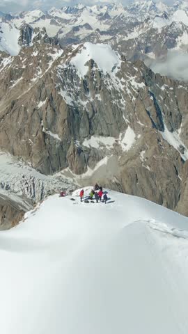 Team of Mountaineers Standing on Snowy Alpine Summit Above Glacier