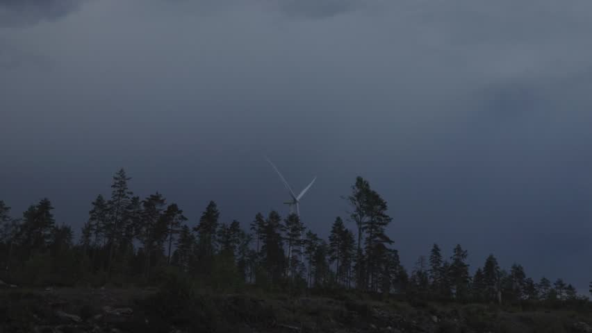 Storm over forest,lightning strikes behind windturbines.