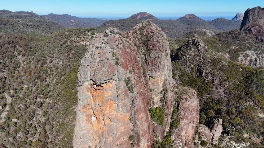 Wide aerial shot of volcanic rock formations under clear blue skies in Warrumbungle National Park.