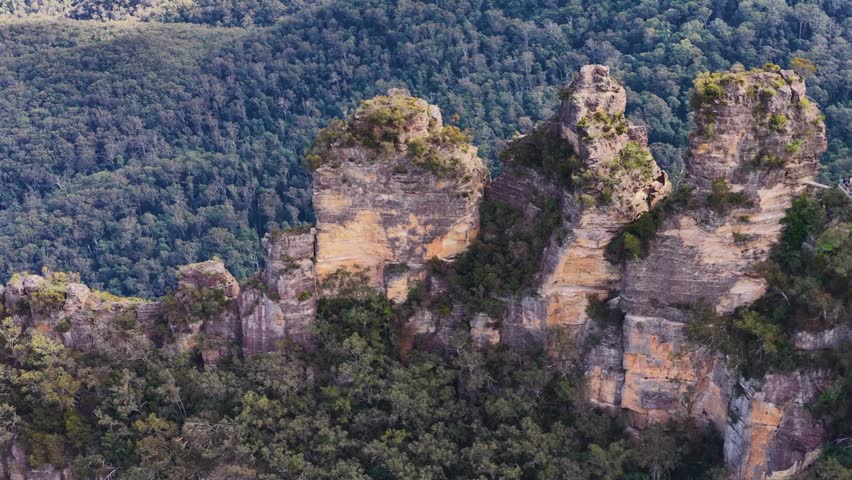 Wide shot of the Three Sisters sandstone peaks under soft daylight in Katoomba, Australia.