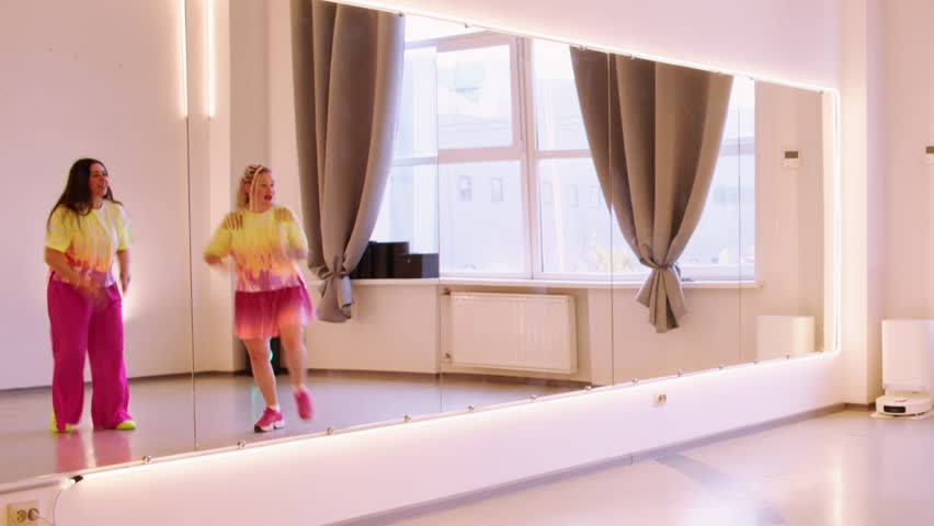 Festive dancer. Funny performance. Happy woman in bright colorful clothes expressive rehearsal moving in mirror light mirror studio.