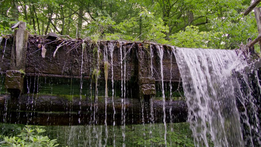 Water flowing at the Mingus Mill in the Great Smoky Mountains National Park in the summer in slow motion tilt down.