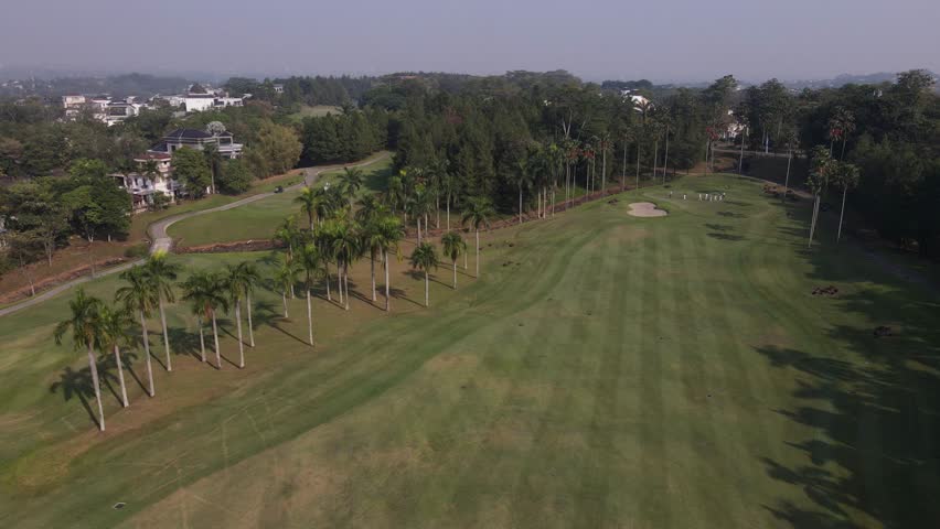 Cinematic aerial drone footage of a beautiful golf course with lush green fairways and golfers playing. Stunning aerial landscape ideal for sports, luxury lifestyle, tourism, resort, recreation, and corporate projects.