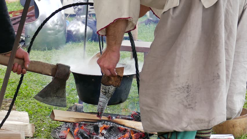 People in medieval outfit are cooking meal