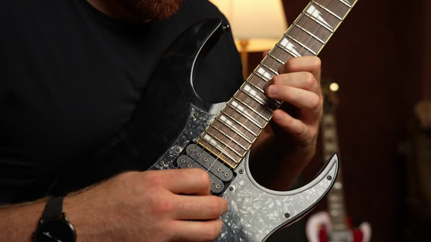 Young guy with ginger beard playing electrical guitar. Strumming and tapping and string picking.