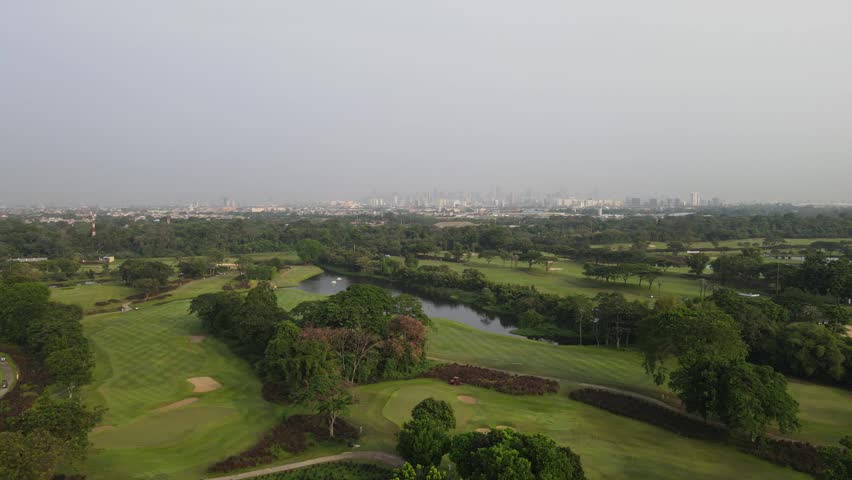 Cinematic aerial drone footage of a beautiful golf course with lush green fairways and golfers playing. Stunning aerial landscape ideal for sports, luxury lifestyle, tourism, resort, recreation, and corporate projects.