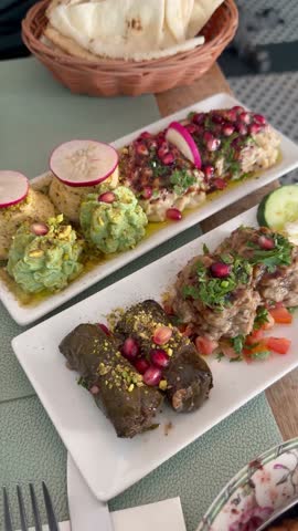 Traditional Lebanese mezze assortment served on plates beside fresh pita during casual restaurant dining.