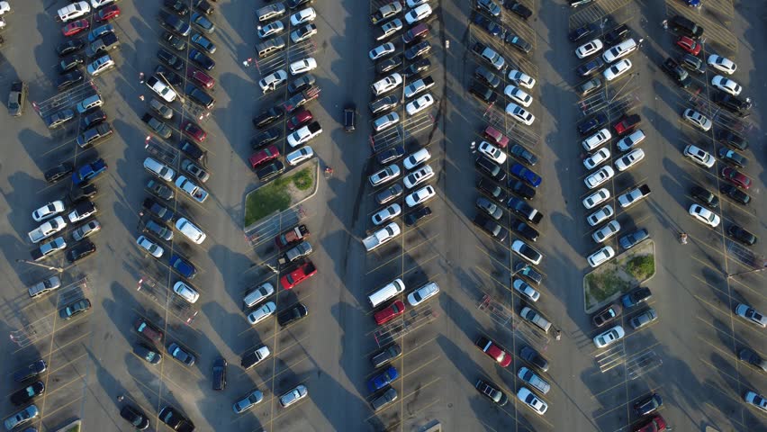 Orderly traffic lanes separate rows of parked cars in Alamo City commercial hub along Potranco Road at peak hours. Active shoppers maneuver past incoming vehicles, San Antonio, Texas. USA