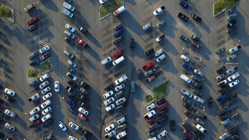 Green landscape islands accent systematic parking spaces filled with West Side grocery shoppers along Potranco Road. Heavy foot traffic moves across wide asphalt bays, San Antonio, Texas. USA