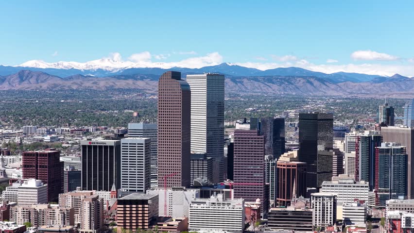 Aerial drone view of Denver downtown skyscrapers with the snow capped Rocky Mountains rising in the distance.