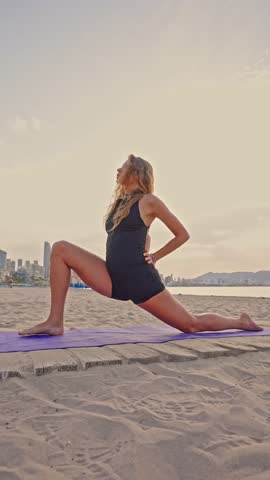 Morning yoga practice takes place on the sand in Benidorm. The sun rises in the background as movements promote flexibility and strength. A calm start to the day.