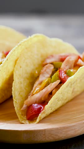 Mexican chicken tacos with bell peppers and onions on wooden table