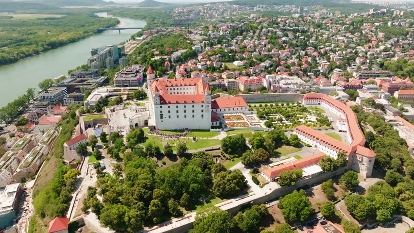 Spectacular aerial drone panorama of Bratislava Castle overlooking the Danube River, castle gardens and the surrounding city. Iconic landmark of Slovakia captured on a sunny summer day.