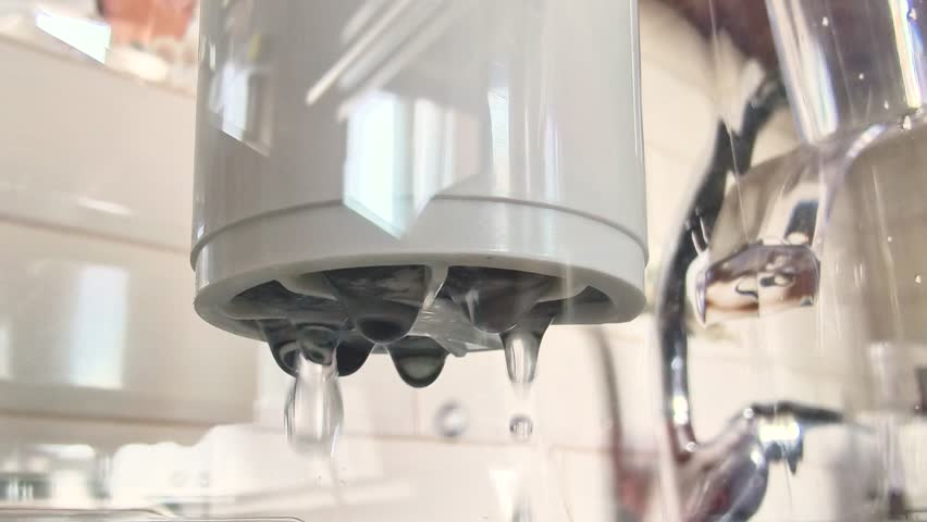 Close-up of falling droplets passing through the water filter cleaning cartridge. The process of water purification at home