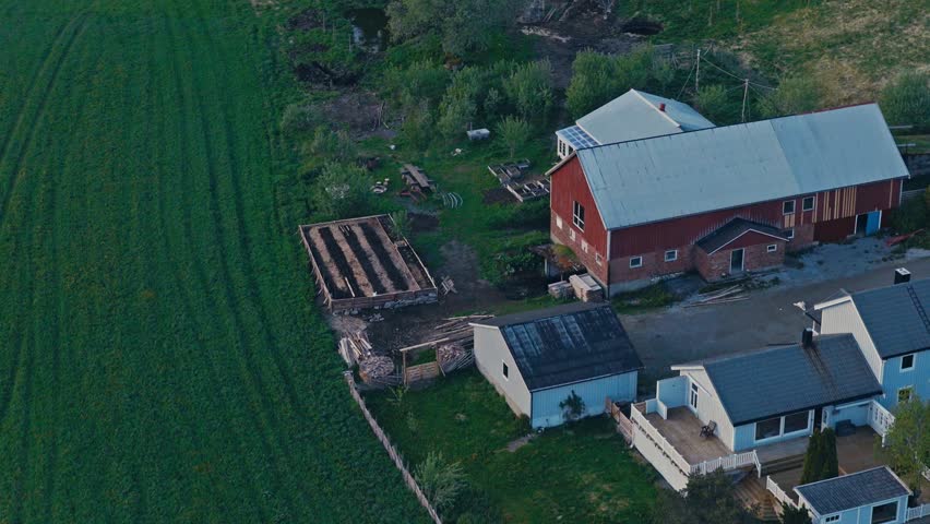 A Rural Farmhouse With A Barn And Raised Garden Beds Surrounded By A Quiet Countryside Landscape. Aerial Shot