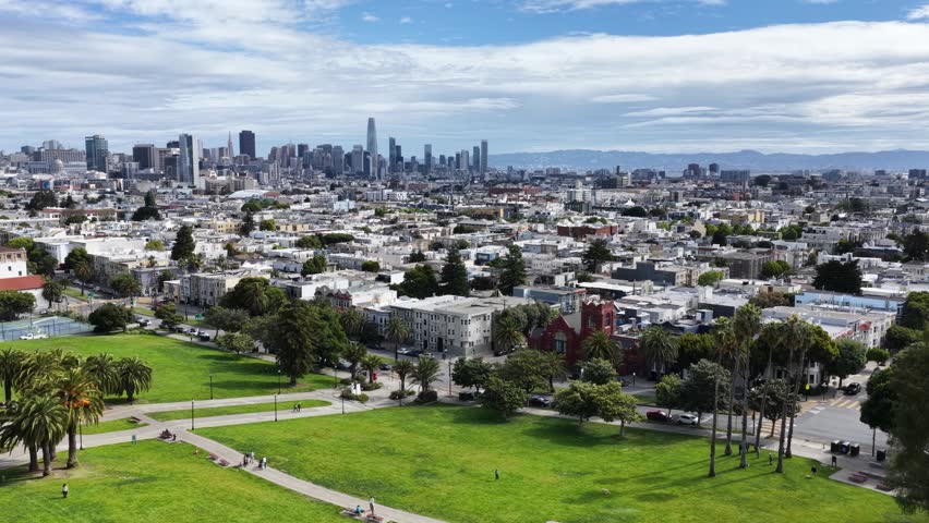 Aerial drone shot panning across Dolores Park with the downtown San Francisco skyline visible in the background.