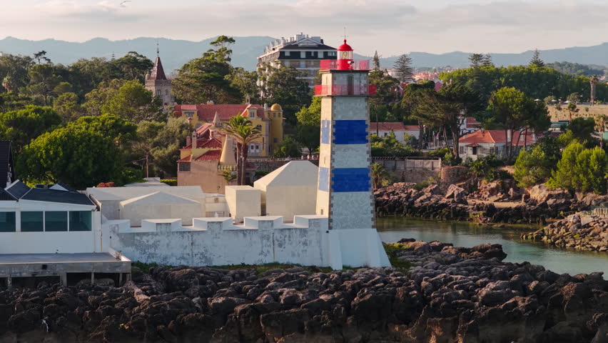 Santa Marta Lighthouse with the Museu Condes de Castro Guimarães overlooking the Atlantic coastline in Cascais, Portugal, during golden hour.