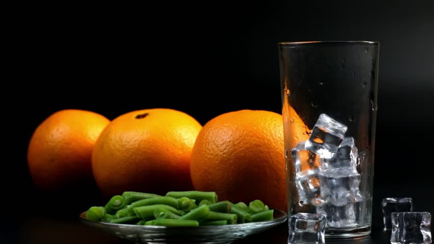 Three oranges and a glass filled with orange juice