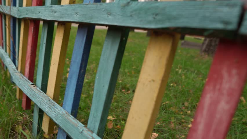 A walk along a colorful fence in a large park
