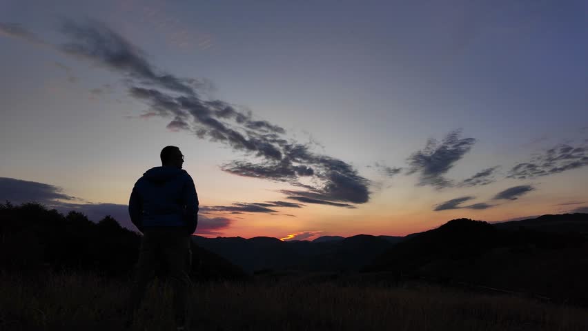 Silhouette of a man looking at the mountain sunset.