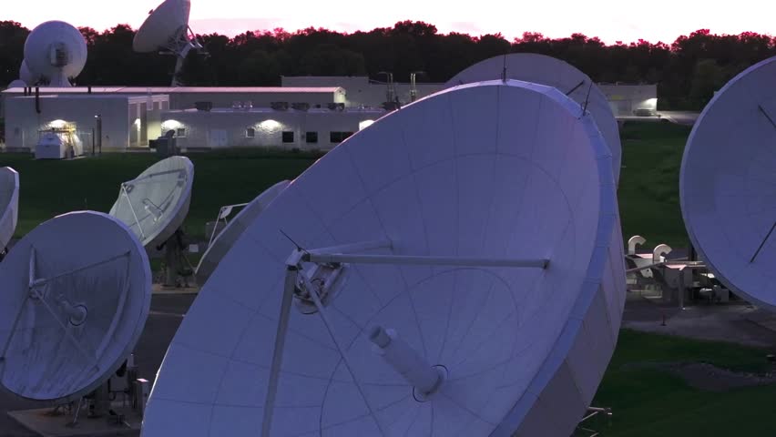 Satellite dishes and radio antennas capture deep space signals at a research facility during a scenic sunset.