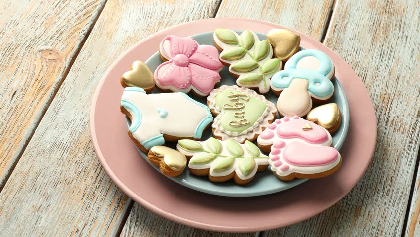 Yummy baby shower cookies on wooden table, rotating
