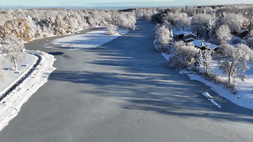 Slow Frozen River Grafton Wisconsin Aerial after Winter Snowstorm, small town and river snow covered