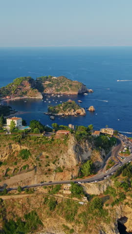 Aerial view of coastal cliffs, winding road, and blue sea near Taormina, Sicily