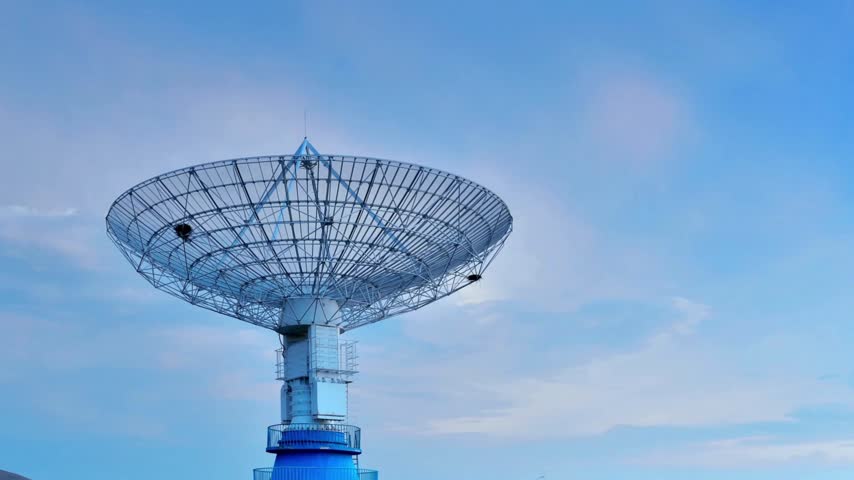 Massive parabolic radio telescope transmitter standing against clear azure heavens capturing signals from deep space for scientific exploration and global telecommunications network technology