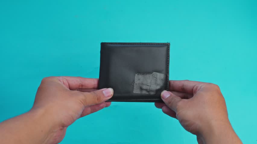 Hands open black wallet and pull out credit card against turquoise background