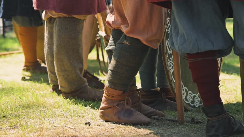 A group of individuals stands together, showcasing various styles of historical clothing while gathered in a grassy area.