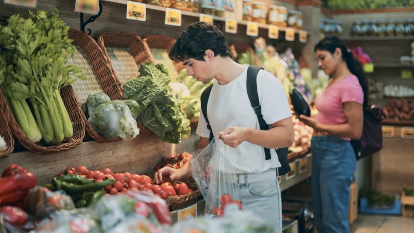 Man shopping, examine vegetable in store and buy elect tomato. Self-service store, organic vegetables and fruits from all over world