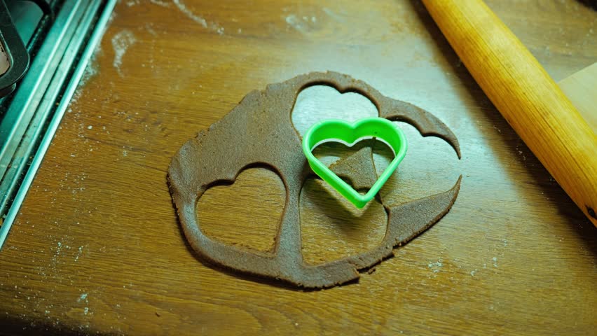 Heart-shaped cookie cutter rests on gingerbread dough ready for baking